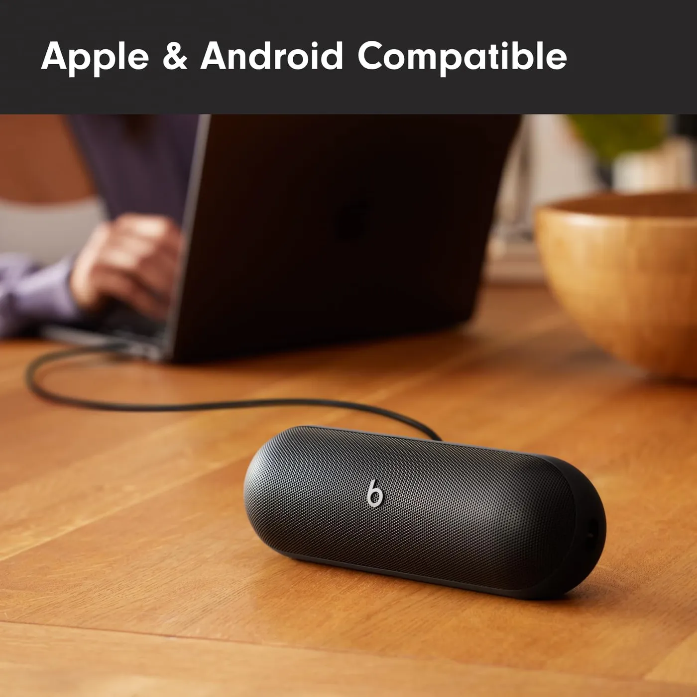 Beats Pill (2024) Bluetooth speaker on a desk next to a laptop, showing Apple and Android compatibility