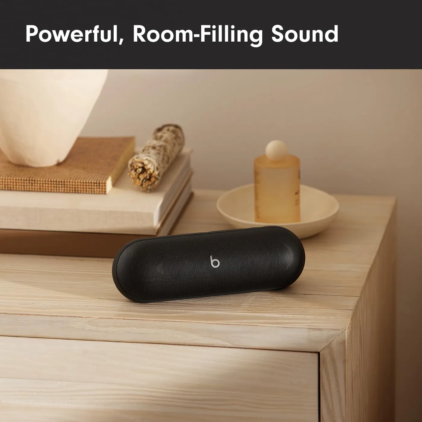 Beats Pill (2024) Bluetooth speaker on a wooden nightstand, illustrating powerful room-filling sound