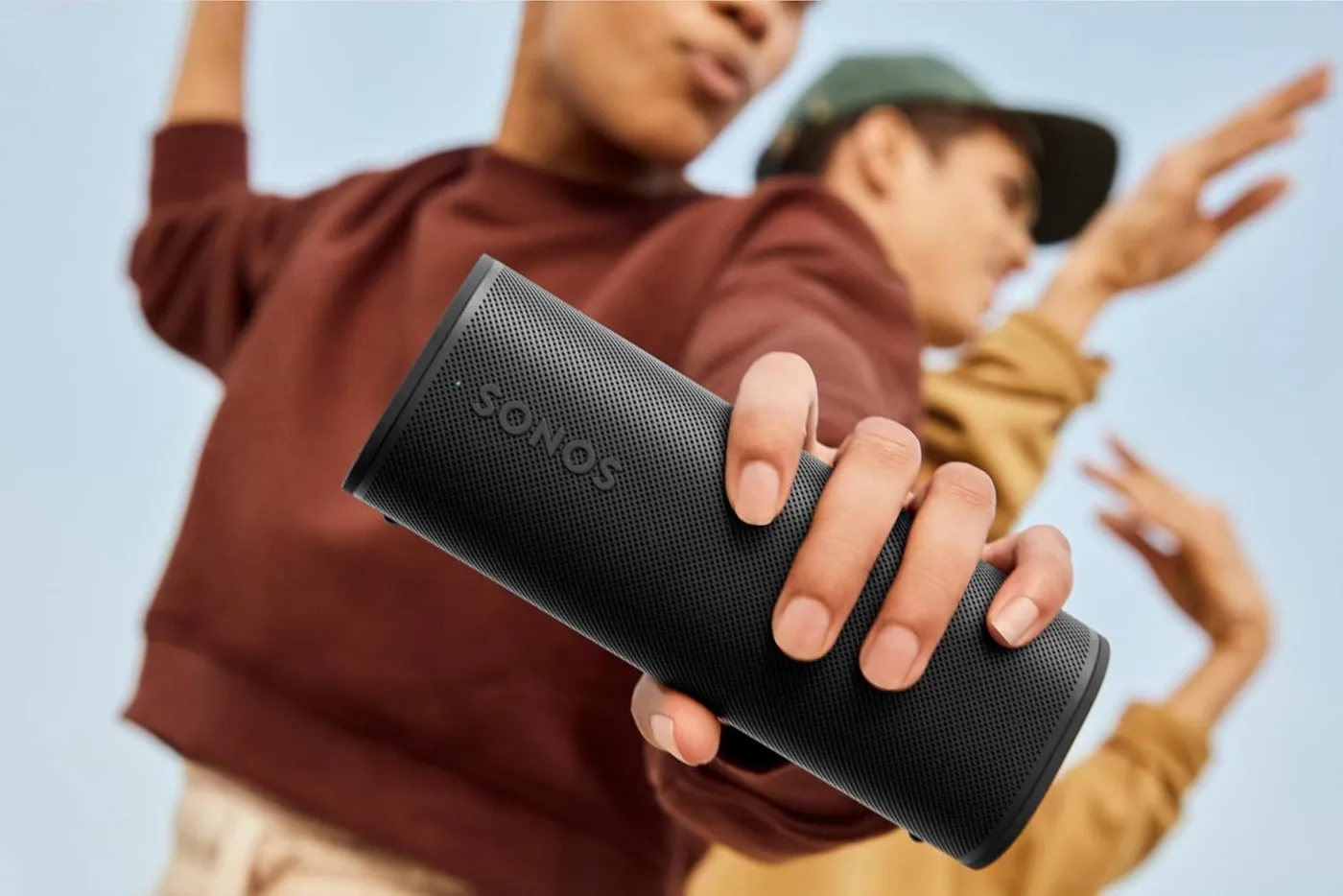 Hand holding the Sonos Roam 2 portable speaker at an outdoor gathering