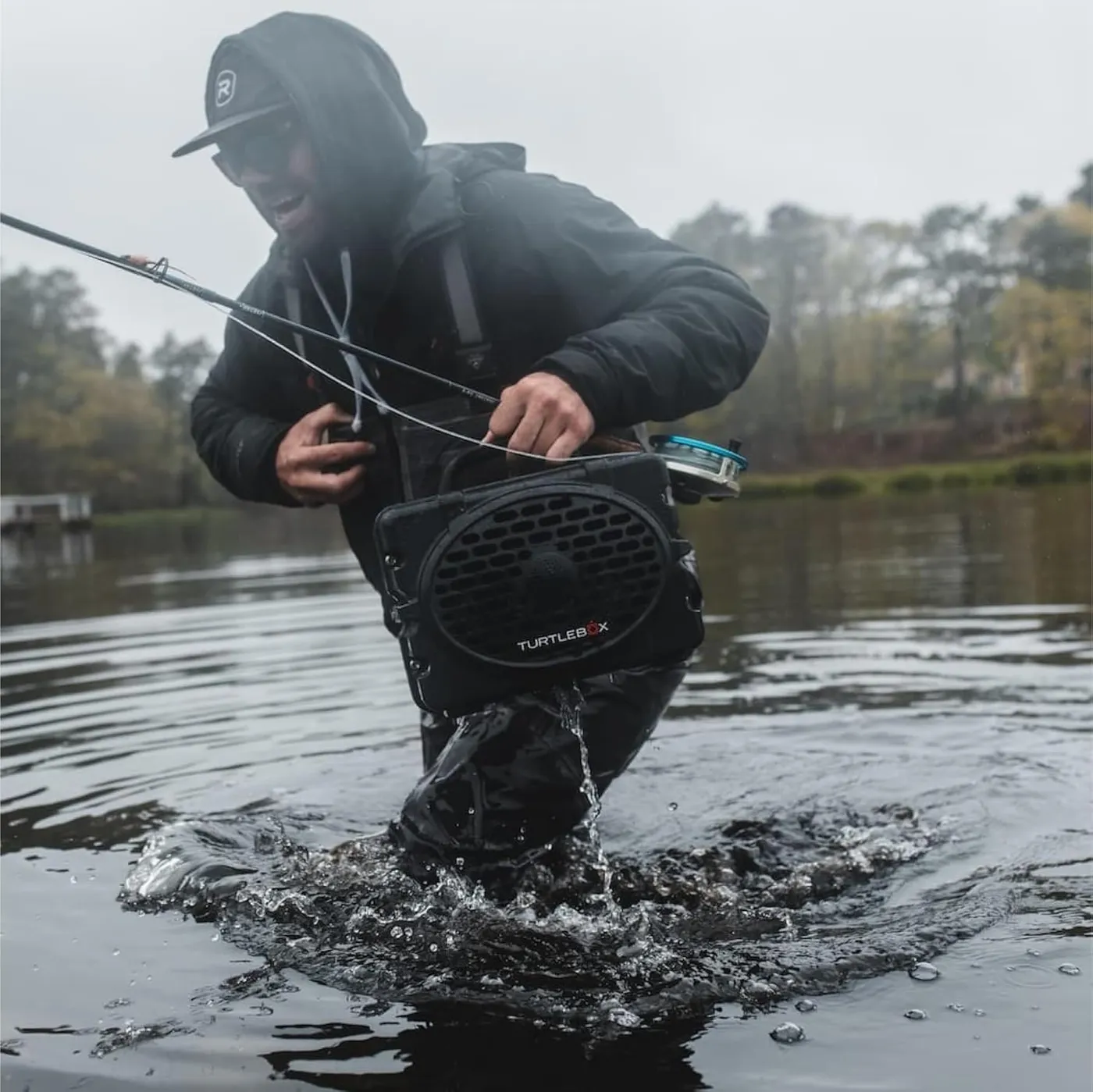 Person fishing in a river with the rugged, waterproof Turtlebox Original Gen 3 Bluetooth speaker
