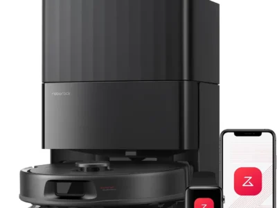 roborock Qrevo S Pro robot vacuum docked at its self-emptying station, with the Roborock app shown on a phone and smartwatch