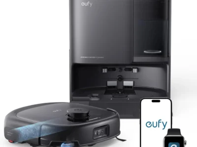 eufy E25 black robot vacuum with roller mop beside its tall all-in-one station, a phone and a smartwatch showing the app