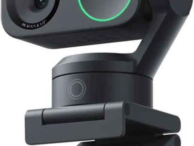 Insta360 Link 2 webcam in black on its folding clip, with a green ring light and gimbal arm