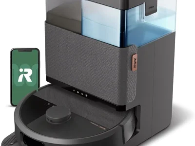 iRobot Roomba 505X black robot vacuum docked at its tall dock with clear dirt and water tanks, beside a phone app