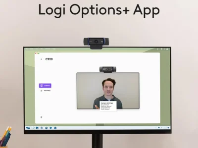 Logitech C920x HD Pro webcam above a monitor showing the Logi Options+ app camera settings screen with a live preview